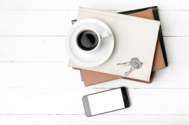 kahve fincanı ile telefon, anahtar ve kitap yığını