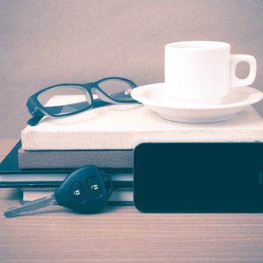 kahve, telefon, araba anahtarı, gözlük ve kitap yığını