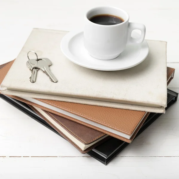 Koffiekopje, sleutel en stapel boek — Stockfoto