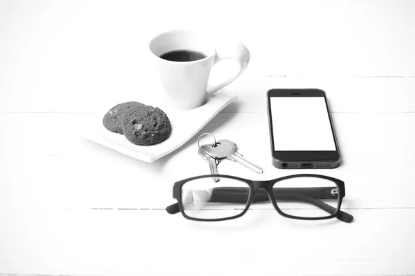 Taza de café con galletas, teléfono, anteojos y llave en blanco y negro — Foto de Stock