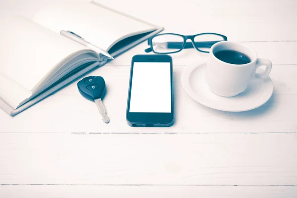 Kaffeetasse mit Telefon, Autoschlüssel, Brille und offenem Notizbuch — Stockfoto