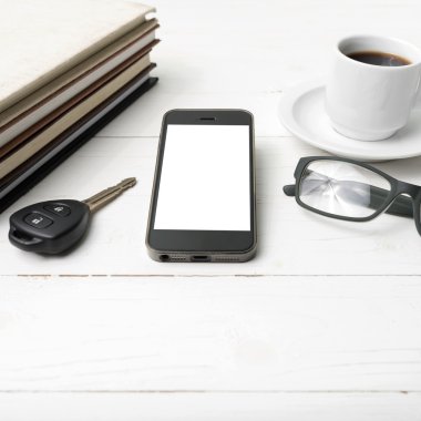 kahve fincanı ile telefon, araba anahtarı, gözlük ve kitap yığını