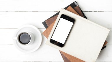 kahve fincanı ile telefon ve kitap yığını