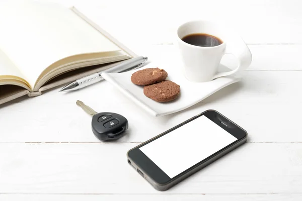 Koffiekopje met cookie, telefoon, open notebook en auto sleutel — Stockfoto