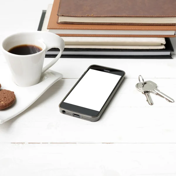 Чашка кави з печивом, телефоном, стосом книги та ключем — стокове фото