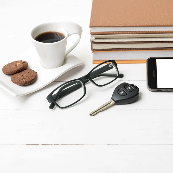 Чашка кави з печивом, телефоном, ключем автомобіля, окулярами та стосом книги — стокове фото