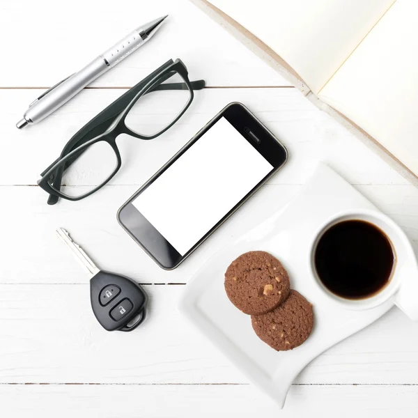 Xícara de café com biscoito, telefone, caderno aberto, chave do carro e eyeglasse — Fotografia de Stock