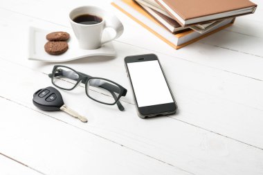Kahve Kupası ile tanımlama bilgisi, telefon, araba anahtarı, gözlük ve kitap yığını