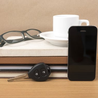 kahve, telefon, araba anahtarı, gözlük ve kitap yığını
