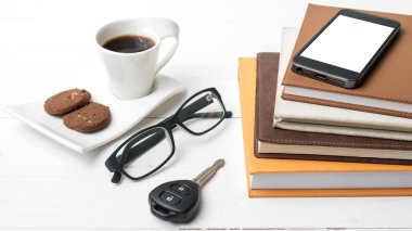 Kahve Kupası ile tanımlama bilgisi, telefon, araba anahtarı, gözlük ve kitap yığını
