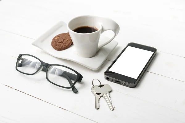 Чашка кави з печивом, телефоном, окулярами та ключем — стокове фото