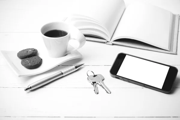 Xícara de café com biscoito, telefone, caderno e chave co preto e branco — Fotografia de Stock