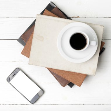 kahve fincanı ile telefon ve kitap yığını