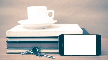 kahve fincanı ile telefon anahtar ve kitap yığını