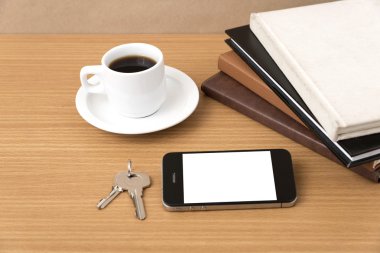 kahve fincanı ile telefon anahtar ve kitap yığını