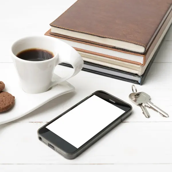 Taza de café con galletas, teléfono, pila de libro y llave — Foto de Stock