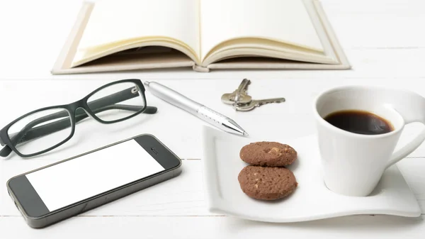 Xícara de café com biscoito, telefone, caderno aberto, chave e óculos — Fotografia de Stock