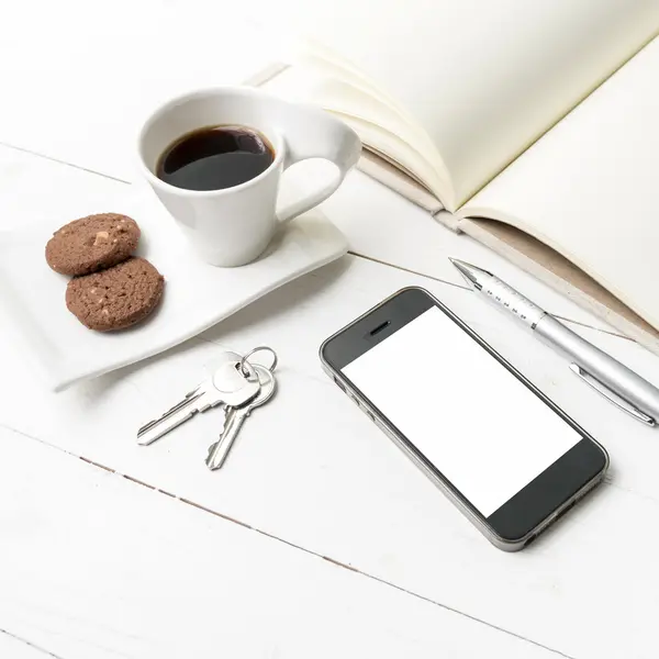 Xícara de café com biscoito, telefone, caderno e chave — Fotografia de Stock