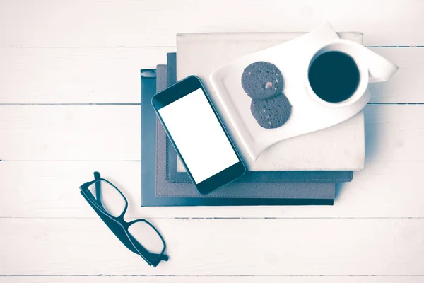 Tasse de café avec cookie, téléphone, pile de livre et lunettes de vue millésime — Photo