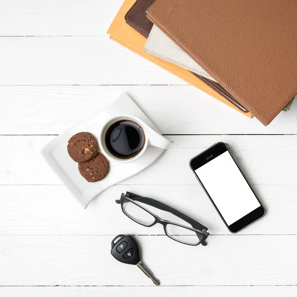 Чашка кави з печивом, телефоном, ключем автомобіля, окулярами та стосом книги — стокове фото