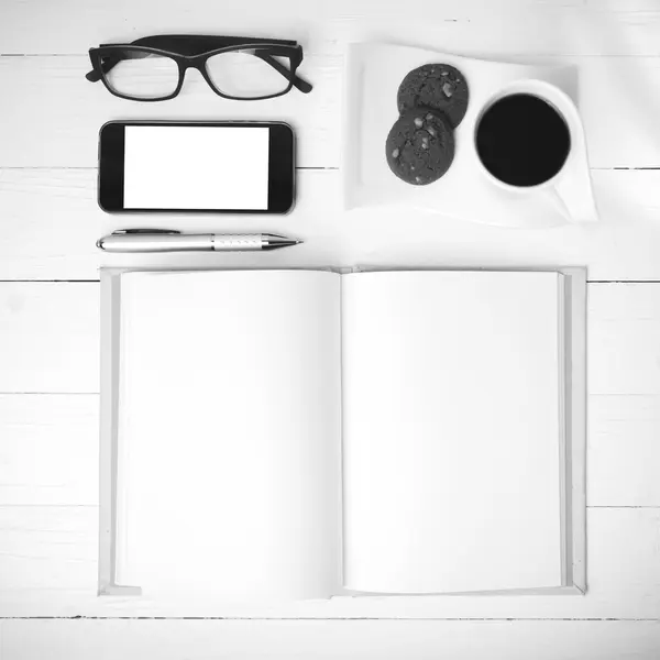 Coffee cup with cookie,phone,notebook and eyeglasses black and w — Stock Photo, Image