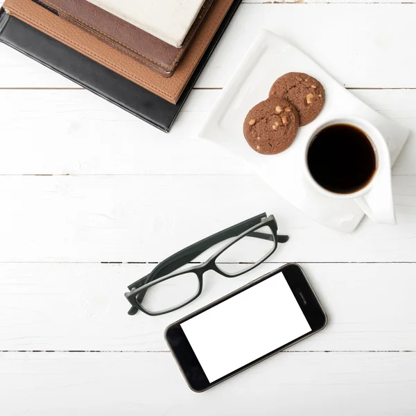 Xícara de café com biscoito, telefone de pilha de livro e óculos — Fotografia de Stock