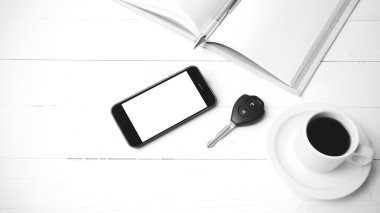 kahve fincanı ile telefon, araba anahtarı ve açık defter siyah ve beyaz 