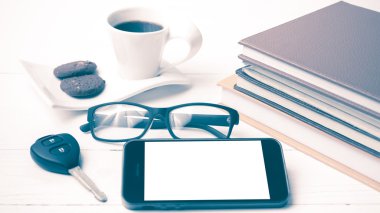 Kahve Kupası ile tanımlama bilgisi, telefon, araba anahtarı, gözlük ve kitap yığını