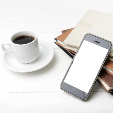 kahve fincanı ile telefon ve kitap yığını