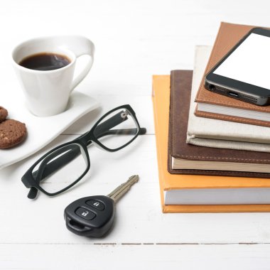 Kahve Kupası ile tanımlama bilgisi, telefon, araba anahtarı, gözlük ve kitap yığını