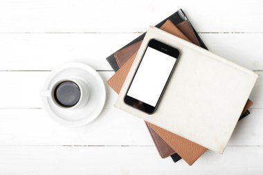 kahve fincanı ile telefon ve kitap yığını