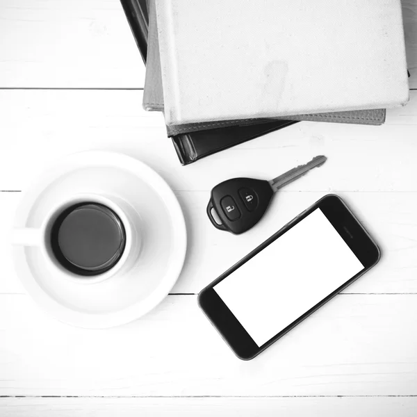 Xícara de café com telefone, chave do carro e pilha de livro preto e branco — Fotografia de Stock