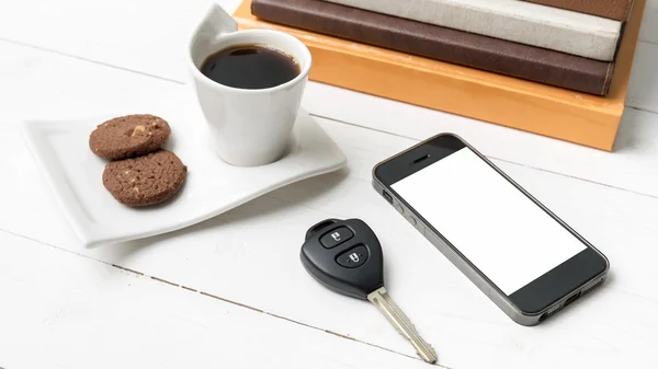 Kávé csésze a cookie-k, a telefon, a autó kulcs és a halom könyv — Stock Fotó