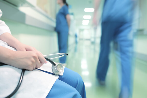 Doctor sitting in hospital corridor on the background of colleag