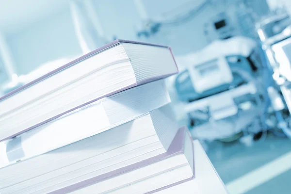 Pile of books on a background of hospital patient bed — Stock Photo, Image