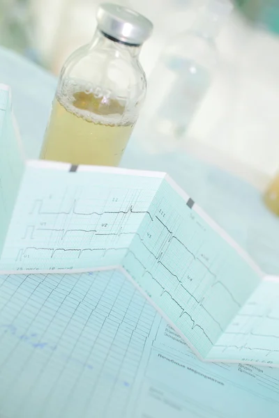 Solution bottle and ecg on the doctors table — Stock Photo, Image