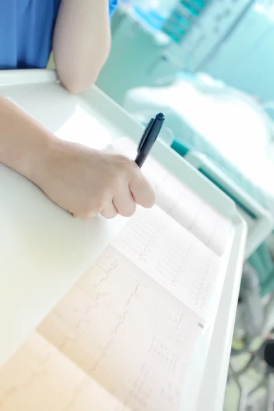 Dokter onderzoekt aandachtig een cardiogram in het ziekenhuis — Stockfoto