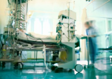Yoğun bakım ünitesinin odaklı olmayan geçmişi, hasta yatağını çevreleyen ekipmanlarla çalışan bulanık tıbbi doktor figürü.. 