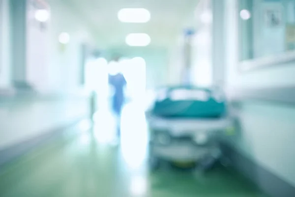 Defocused background of walking human silhouette against the blinding light in the hospital hallway.