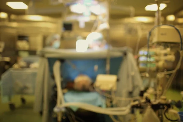 Blurred hospital surgery room with working surgeons and patient on the table, unfocused background.