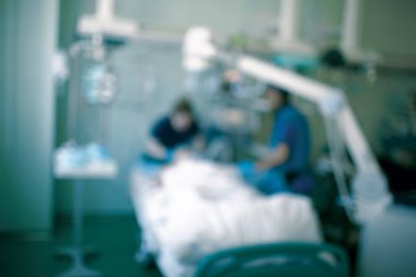 Doktor ve hemşire yoğun bakımdaki yatakta odaklanmamış bir örnekle çalışıyorlar..