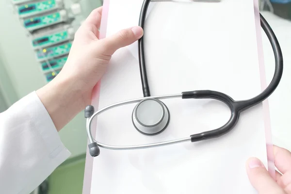 Doctor con un portapapeles y un estetoscopio en una encuesta del paciente —  Fotos de Stock
