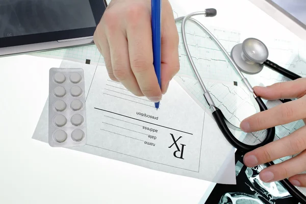 Médico escrevendo uma receita médica na mesa — Fotografia de Stock