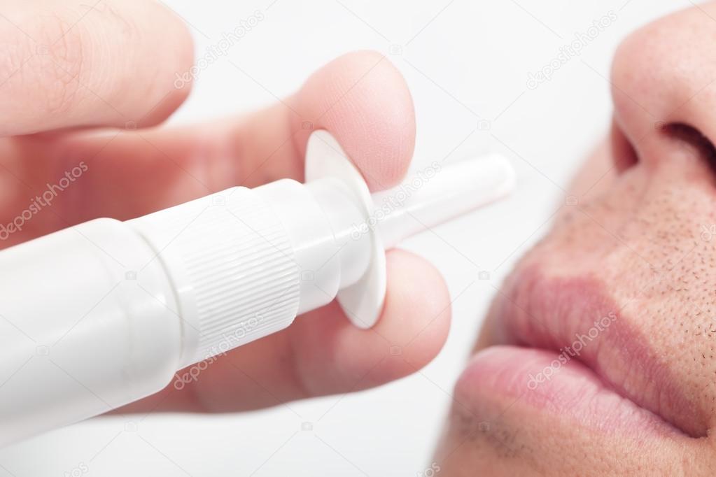 Man sprays medicine for allergy in nose