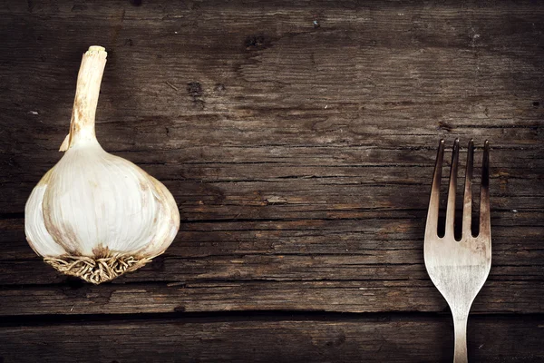 Garlic and fork on old cracked board