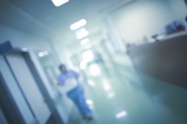 Hastane koridorda yürüyen doktor ile odaklanmamış arka plan