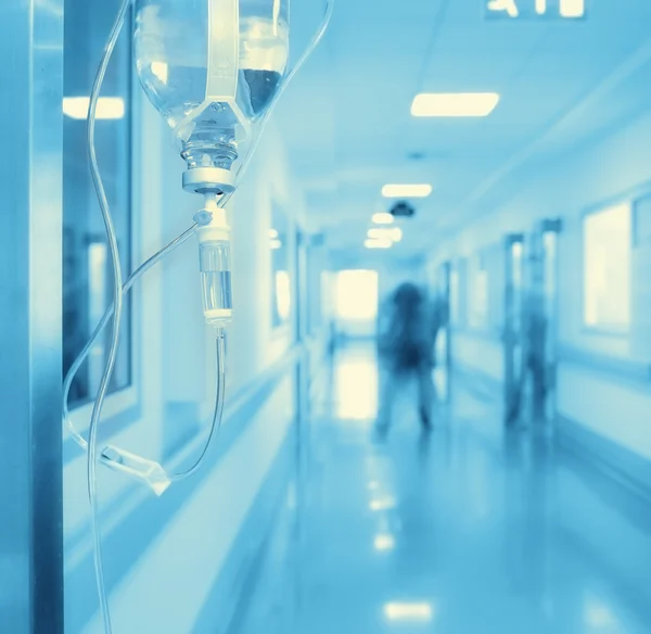 Goteo Iv en el pasillo del hospital en el fondo de silueta extraña — Foto de Stock