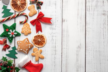 Noel arkaplanında zencefilli kurabiyeler, beyaz ahşap bir masada Noel ağacı süslemeleri, yazı yazmak için yer.