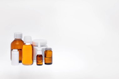 Farklı kavanozlardaki ilaçlar, kaplar, tüpler, şuruplar, tentürler, yağlar ve spreyler. Eczane kavramı, laboratuvar, ilk yardım çantası, beyaz bir arka plan. Boş alan, sağ taraftaki metin için boşluk