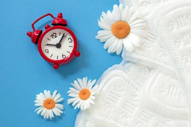 feminine sanitary pads, white chamomile flowers, alarm clock on blue background, concept of feminine health and hygiene, menopause, periodic menstruation clipart
